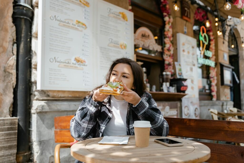 Mujer comiendo tranquilamente en cafetería, ejemplo de alimentación flexible y consciente sin restricciones